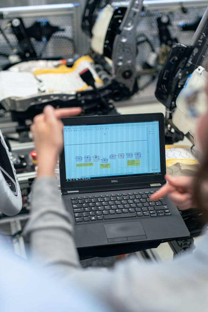 services-02 Engineers using a laptop to analyze software data in an industrial workshop setting.